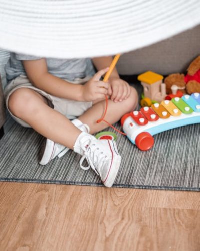 child sitting on floor and playing with xylophone toy