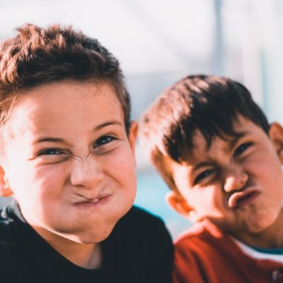 shallow focus photography of two boys doing wacky faces